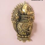 IMG_6164 - thebrasshandicrafts.com Ornate brass decorative sculpture with intricate patterns and a crown-like top, displayed on a pink wall. thebrasshandicrafts.com