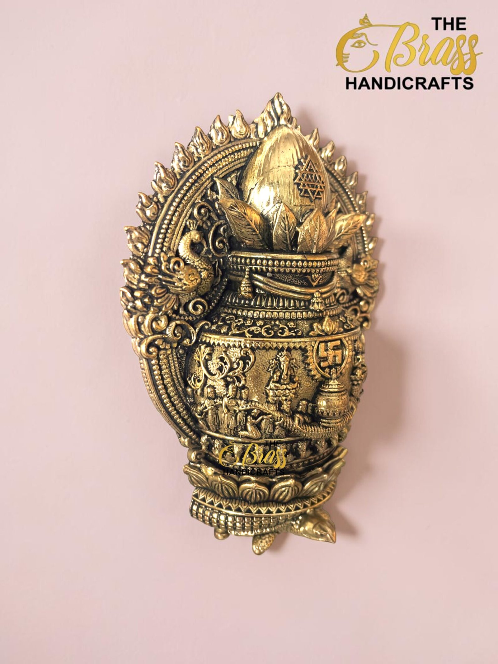 IMG_6164 - thebrasshandicrafts.com Ornate brass decorative sculpture with intricate patterns and a crown-like top, displayed on a pink wall. thebrasshandicrafts.com