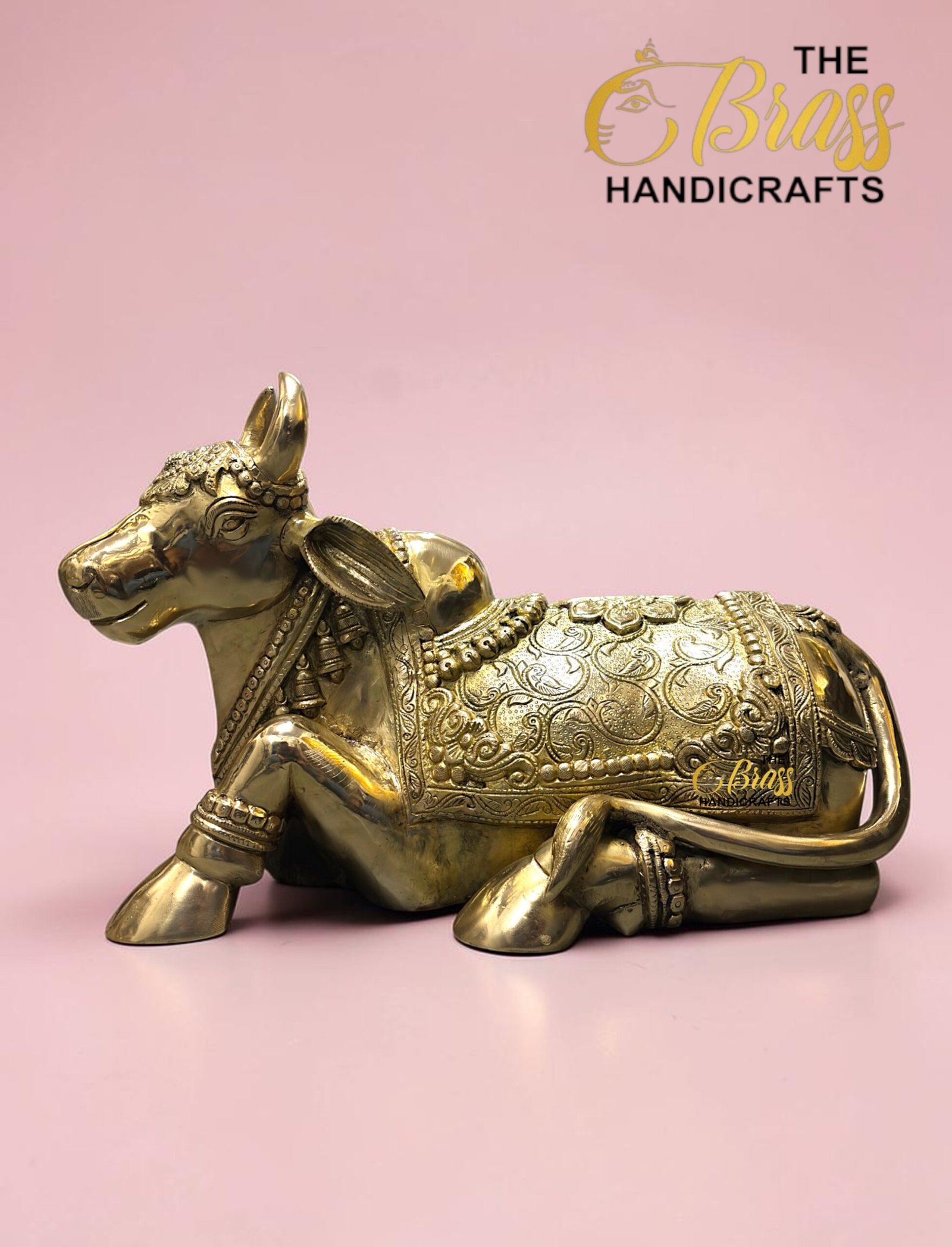 Ornate gold brass elephant statue with intricate engravings on a pink background; The Brass Handicrafts logo in the top right corner  thebrasshandicrafts.com