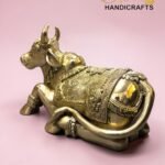 Gold decorative brass bull statue with intricate engravings on a pink background.  thebrasshandicrafts.com