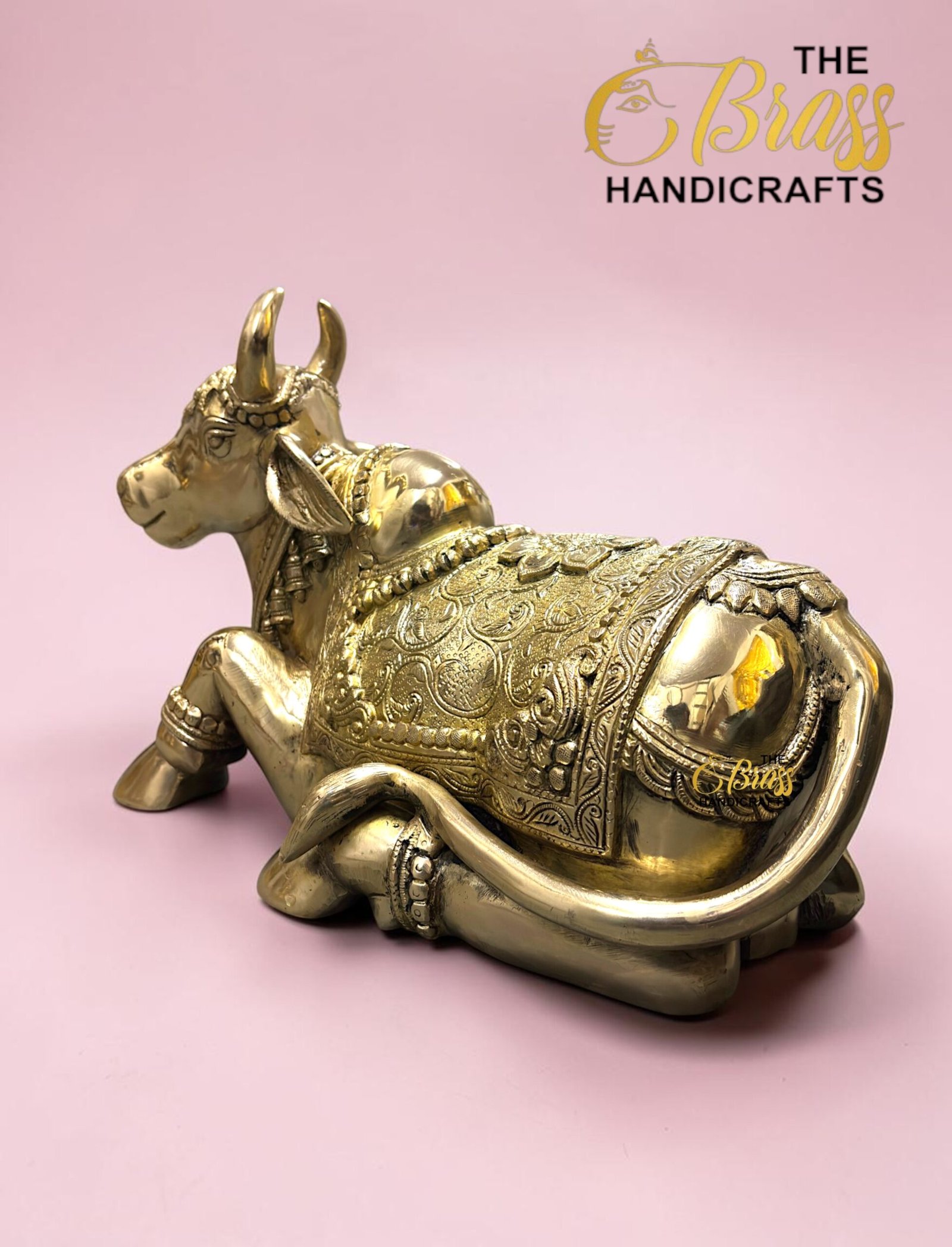 Gold decorative brass bull statue with intricate engravings on a pink background.  thebrasshandicrafts.com