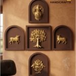 panch tatva 2 - thebrasshandicrafts.com Wall with brown arched frames displaying gold craft figures and a tree centerpiece; branding reads 'The Brass Handicrafts' in gold on the right. thebrasshandicrafts.com