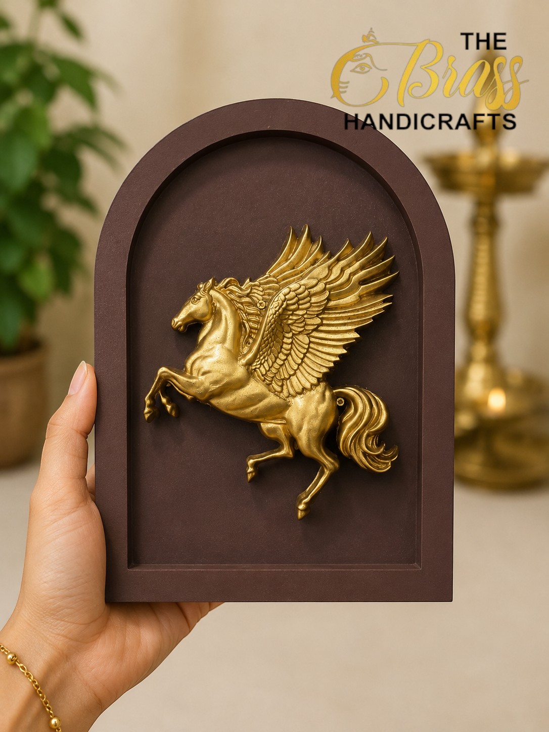 Hand holds a brown arched plaque with a gold Pegasus relief.  thebrasshandicrafts.com