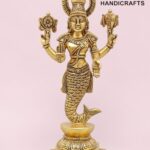 Gold-colored brass statue of a Hindu deity with a fish tail, standing on a decorative pedestal against a pink background.  thebrasshandicrafts.com