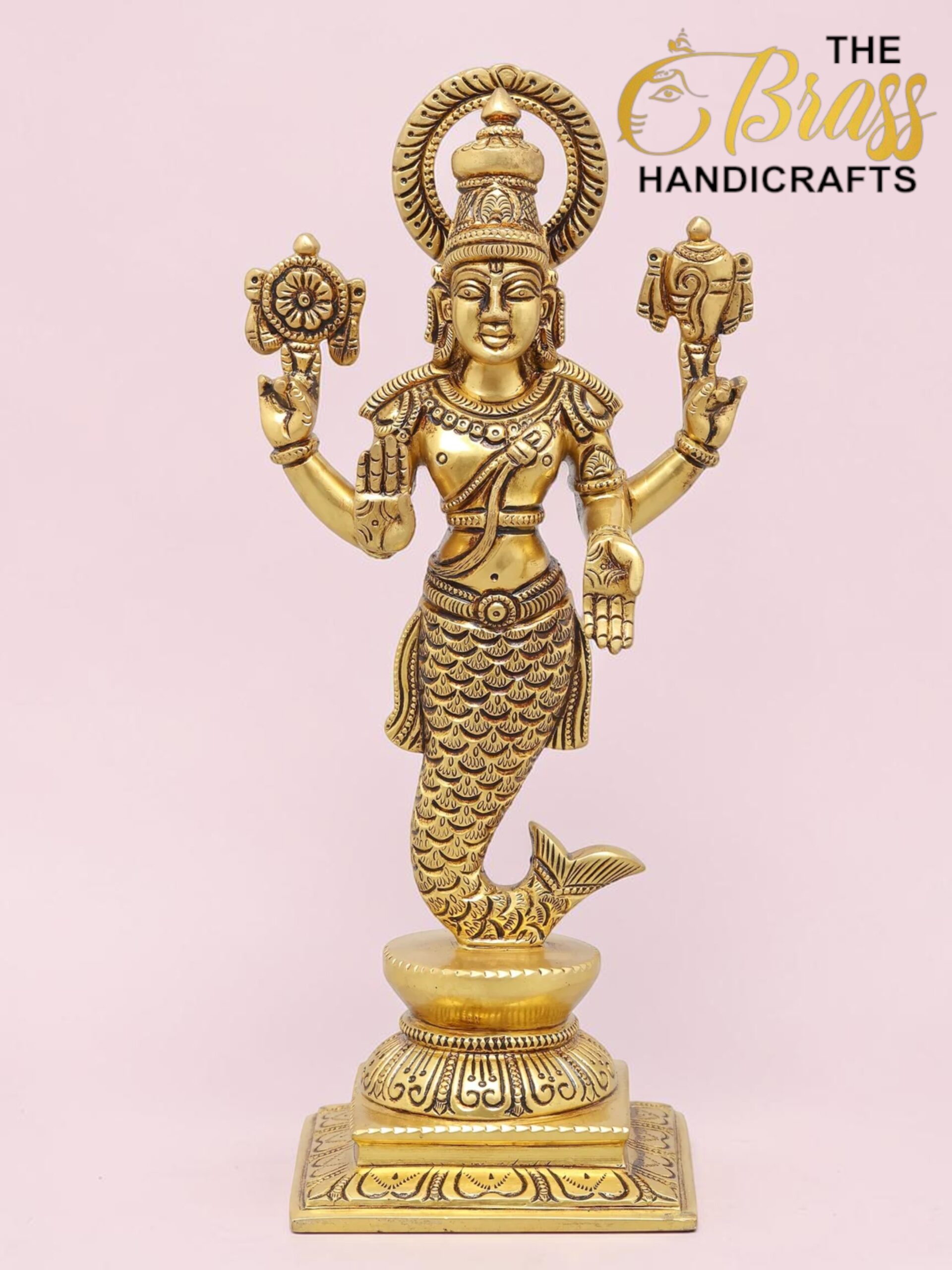 Gold-colored brass statue of a Hindu deity with a fish tail, standing on a decorative pedestal against a pink background.  thebrasshandicrafts.com