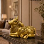 Gold-toned decorative bull statue with ornate detailing on a marble surface in a luxurious interior. - The Brass Handicrafts setting appears in the scene.  thebrasshandicrafts.com