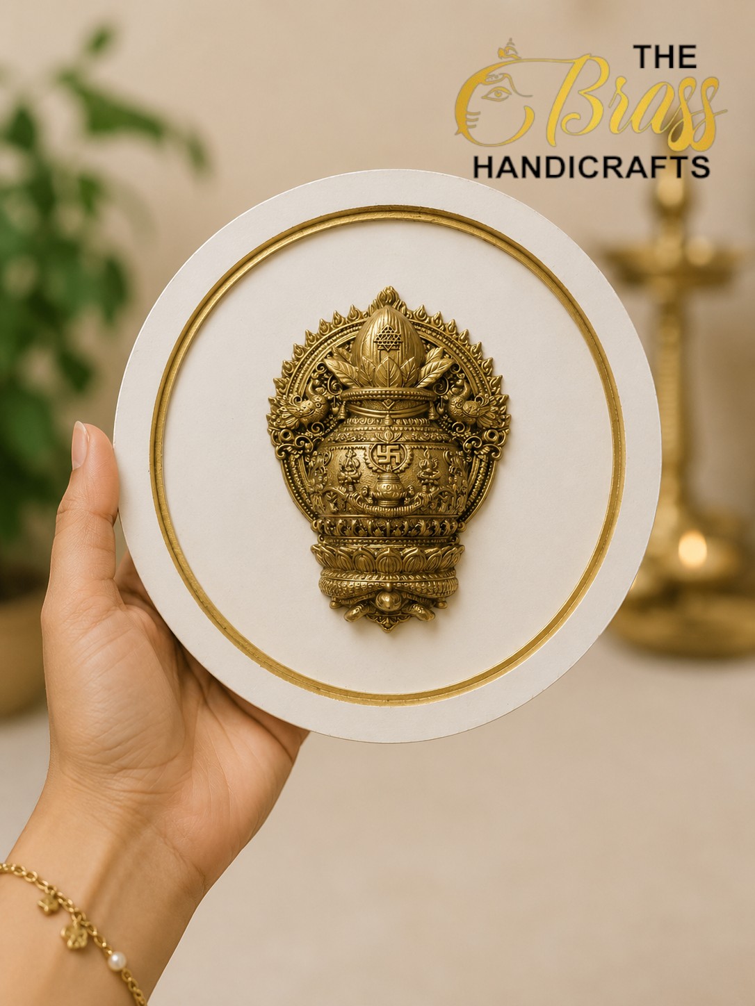 Hand holding a circular white display plate with a detailed gold brass ornament in the center. The Brass Handicrafts logo appears in the background.  thebrasshandicrafts.com