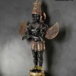 Bronze and gold statue of Garuda with detailed headdress and outstretched wings, standing on a gold pedestal (The Brass Handicrafts logo top right).  thebrasshandicrafts.com