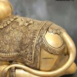 nandi 6 - thebrasshandicrafts.com Gold-toned Buddha statue with intricate carved patterns, shown reclining with a scroll-like arm; logo 'The Brass Handicrafts' visible in corner thebrasshandicrafts.com