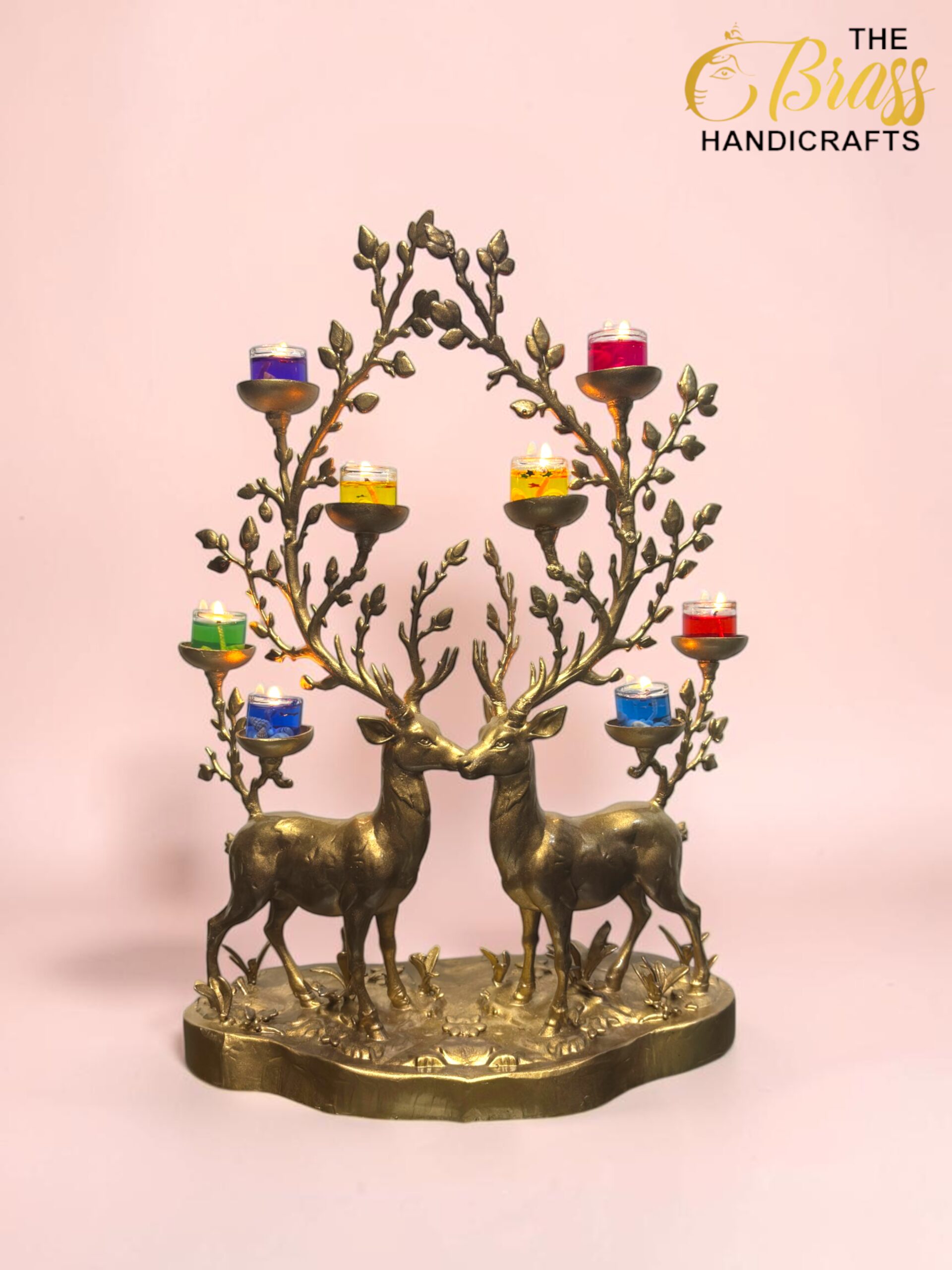 Brass candle holder shaped as two deer with colorful glass tealight cups on branching arms against a pink background.  thebrasshandicrafts.com