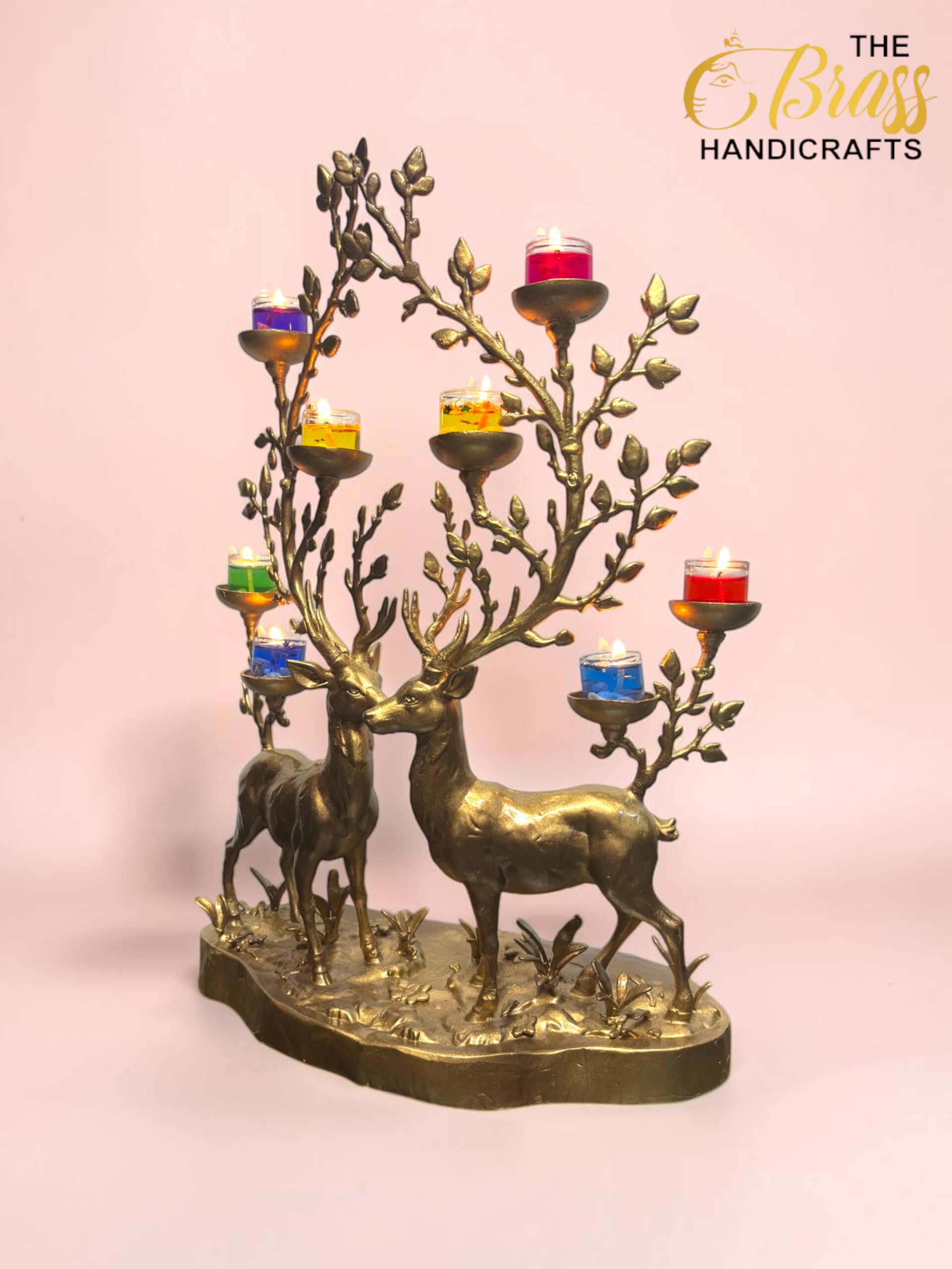 Brass deer candle tree sculpture with multicolored glass candle holders against a pink backdrop (The Brass Handicrafts logo visible).  thebrasshandicrafts.com