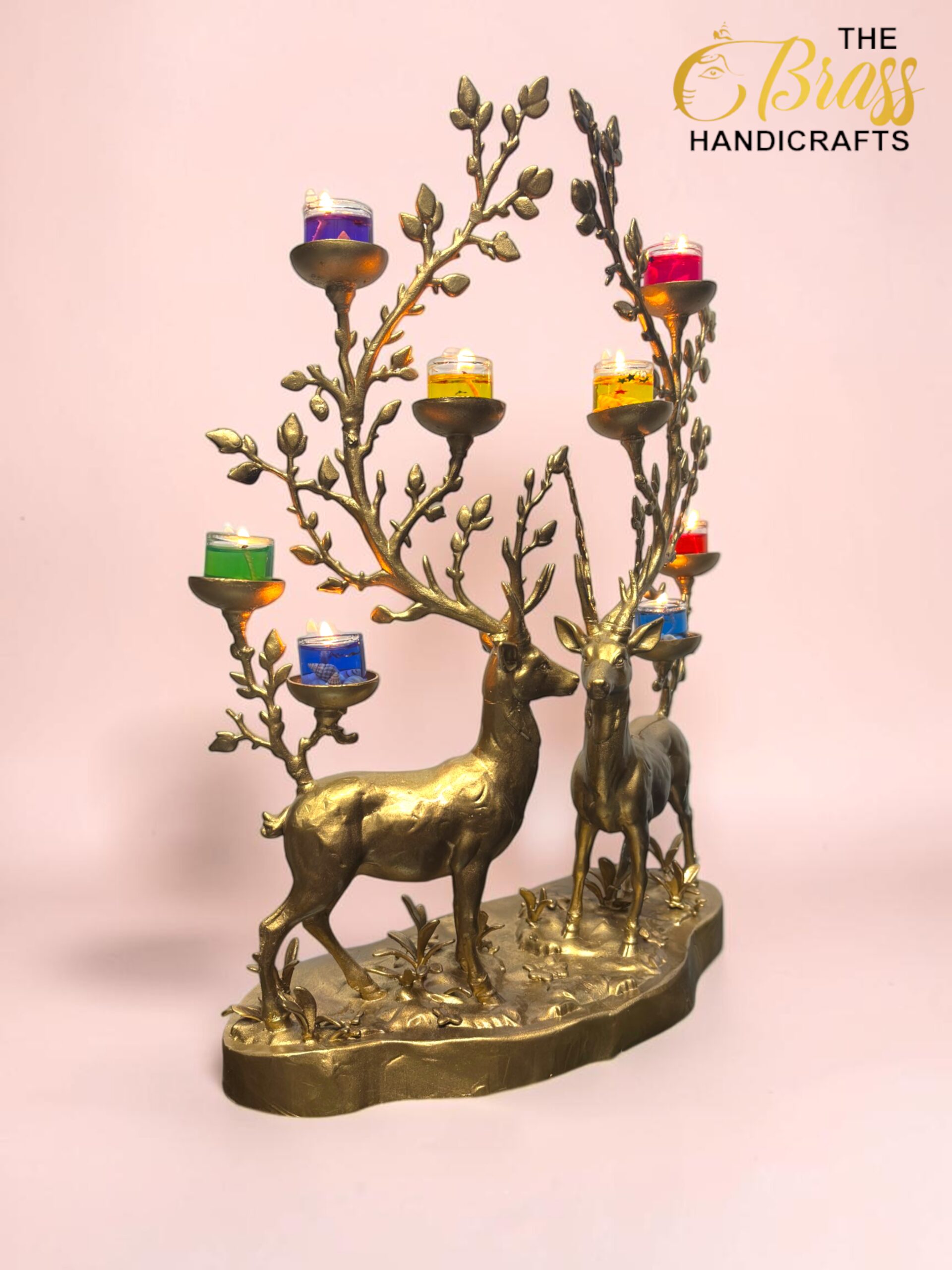 Gold-toned deer-shaped candelabra with multiple branched antlers holding small colored candles against a pink background.  thebrasshandicrafts.com
