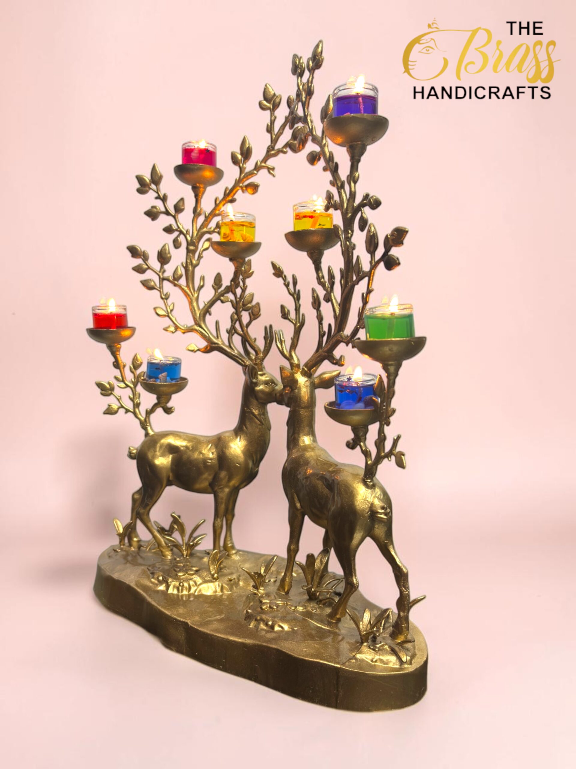 Bronze decorative candle holder featuring two deer and leafless branches with multicolored small candle cups against a pink wall.  thebrasshandicrafts.com