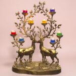 Ornate brass candelabra shaped by two deer whose branches hold multicolored tea candles in glass cups.  thebrasshandicrafts.com