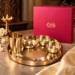 Pink box labeled The Brass Handicrafts beside a gold brassware set on a reflective tray.  thebrasshandicrafts.com