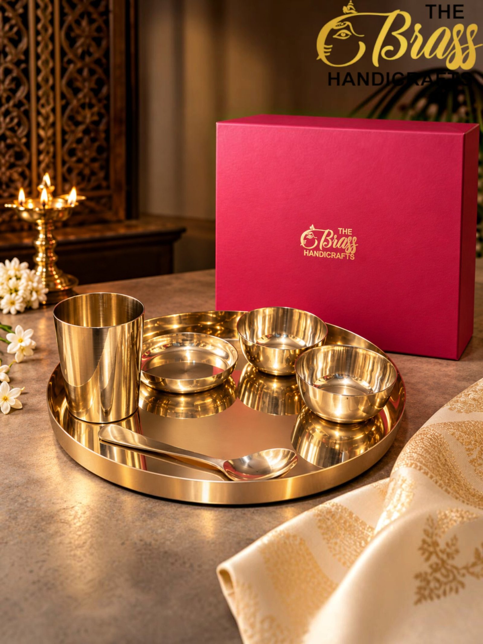 Pink box labeled The Brass Handicrafts beside a gold brassware set on a reflective tray.  thebrasshandicrafts.com