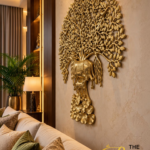 Golden Tree of Life in a Luxe Living Room 1 1 - thebrasshandicrafts.com Gold metal tree wall sculpture with intricate leaves on a beige wall beside a lamp and sofa in a luxurious living room. thebrasshandicrafts.com
