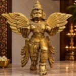 Winged Brass Deity in Golden Shrine Light - thebrasshandicrafts.com Gold statue of Garuda with outstretched wings on a marble surface, showing intricate engravings and adornments on a warm-toned display. thebrasshandicrafts.com