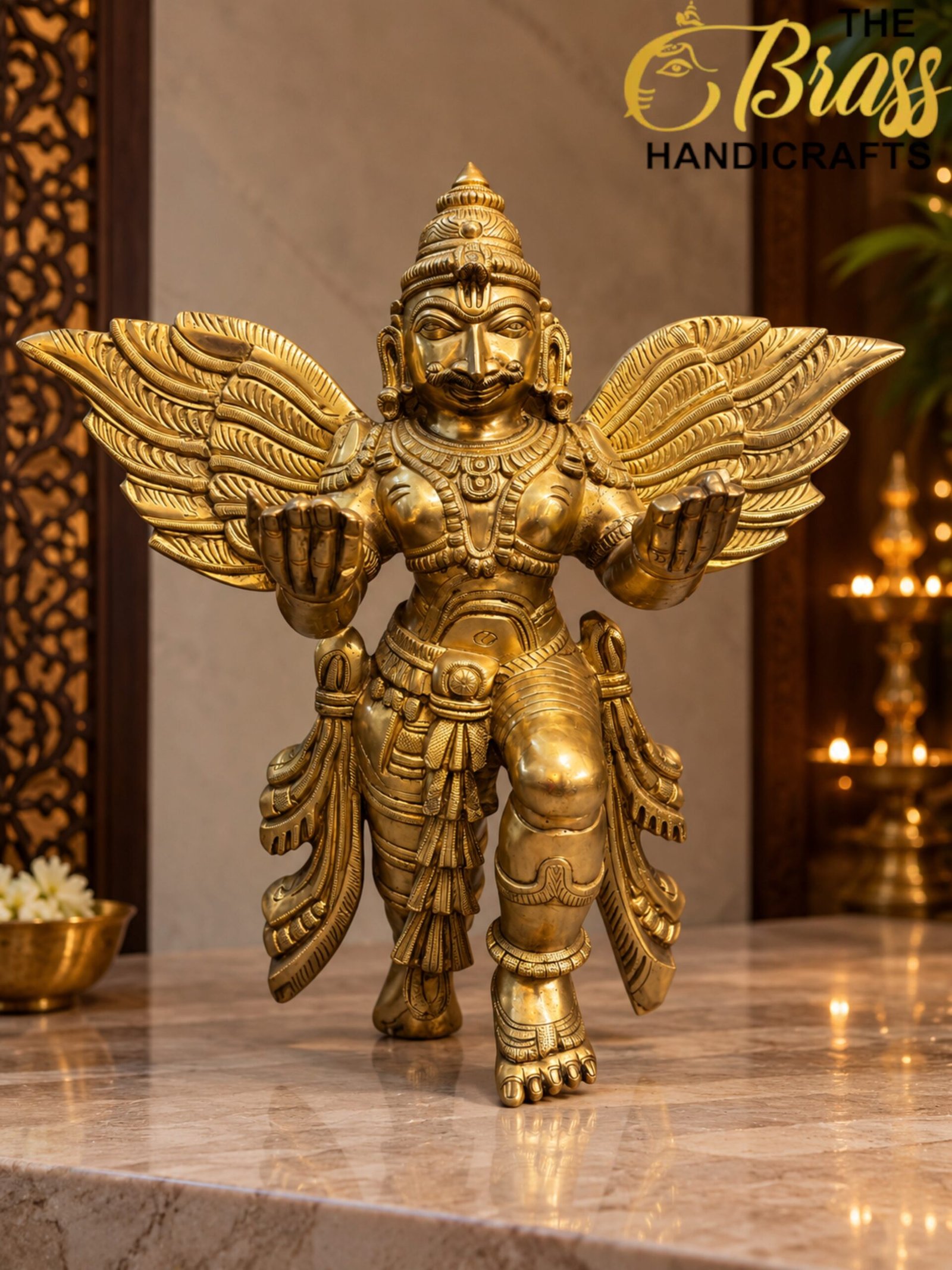 Winged Brass Deity in Golden Shrine Light - thebrasshandicrafts.com Gold statue of Garuda with outstretched wings on a marble surface, showing intricate engravings and adornments on a warm-toned display. thebrasshandicrafts.com