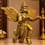 Winged Brass Deity on Marble - thebrasshandicrafts.com Golden winged deity statue on a marble pedestal in a showroom, with 'The Brass Handicrafts' logo visible in the top right corner. thebrasshandicrafts.com