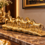 horses 3 - thebrasshandicrafts.com Row of golden horse statues arranged along a marble countertop with a framed artwork in the background. thebrasshandicrafts.com