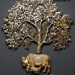 Decorative gold tree sculpture growing from a gold elephant on a dark wall background.”],  thebrasshandicrafts.com