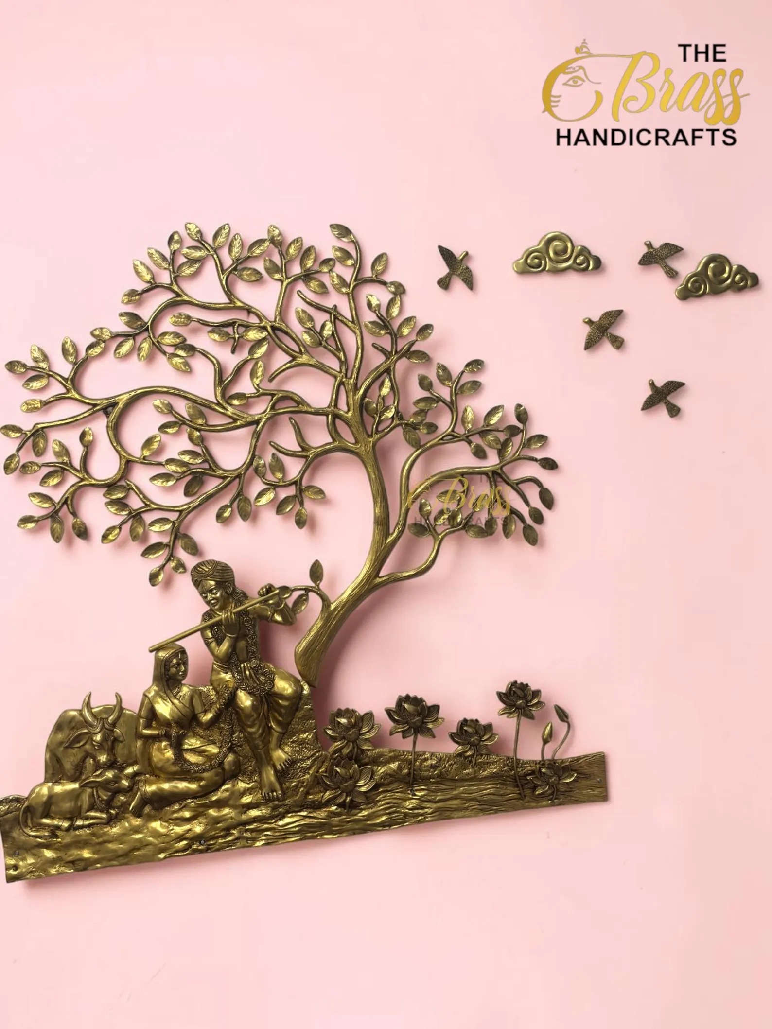 il_1588xN8446713239_b6u1 - thebrasshandicrafts.com Brass tree sculpture with a seated couple beneath branches on a pink background; logo The Brass Handicrafts in the corner. thebrasshandicrafts.com