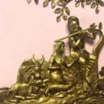 il_1588xN8446713259_1ye0 - thebrasshandicrafts.com Gold-tone brass sculpture of a fluting figure (Krishna) riding a cow, with ornate jewelry and a decorative branch pattern in the background on a pink surface. thebrasshandicrafts.com