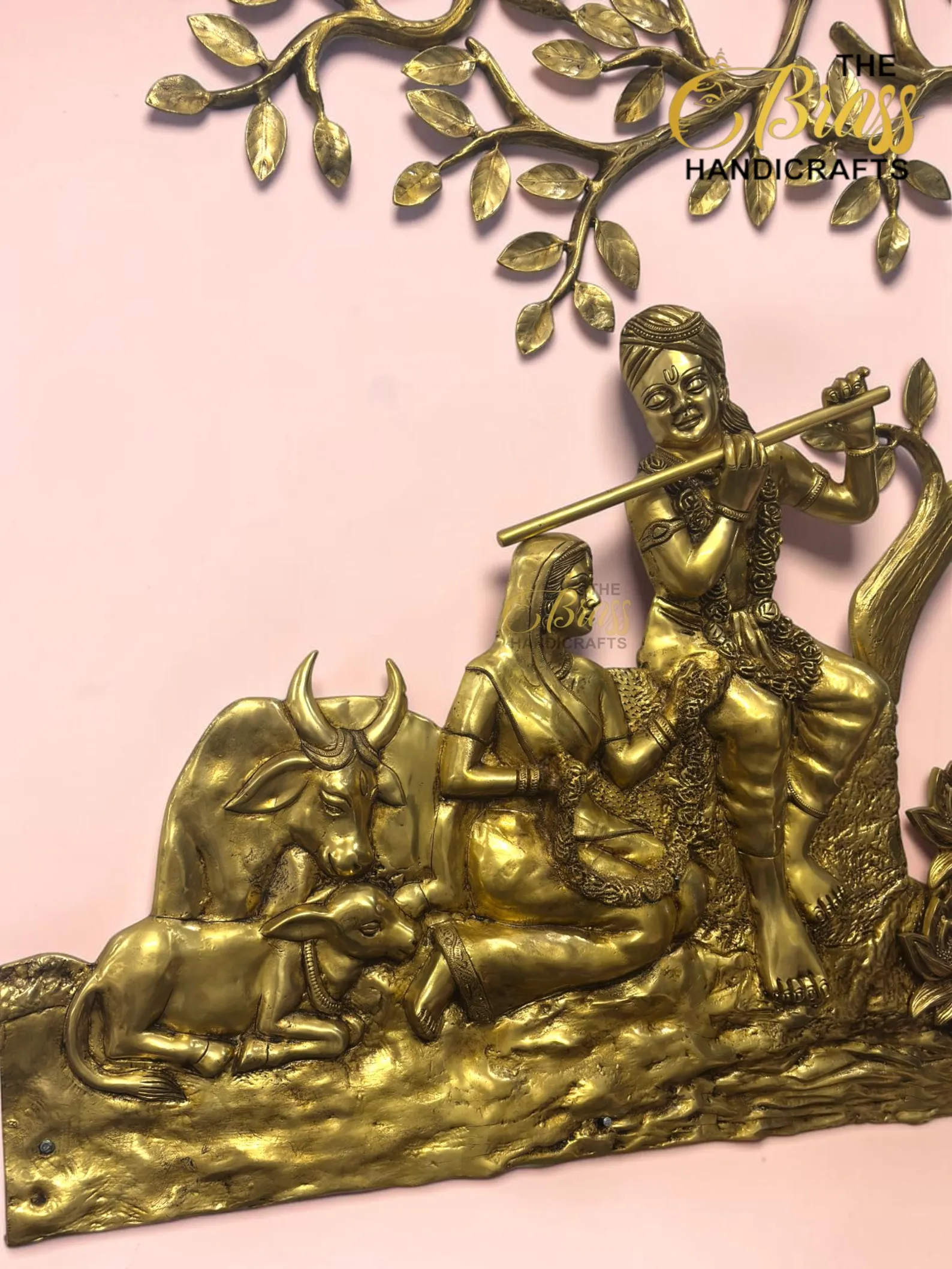 il_1588xN8446713259_1ye0 - thebrasshandicrafts.com Gold-tone brass sculpture of a fluting figure (Krishna) riding a cow, with ornate jewelry and a decorative branch pattern in the background on a pink surface. thebrasshandicrafts.com