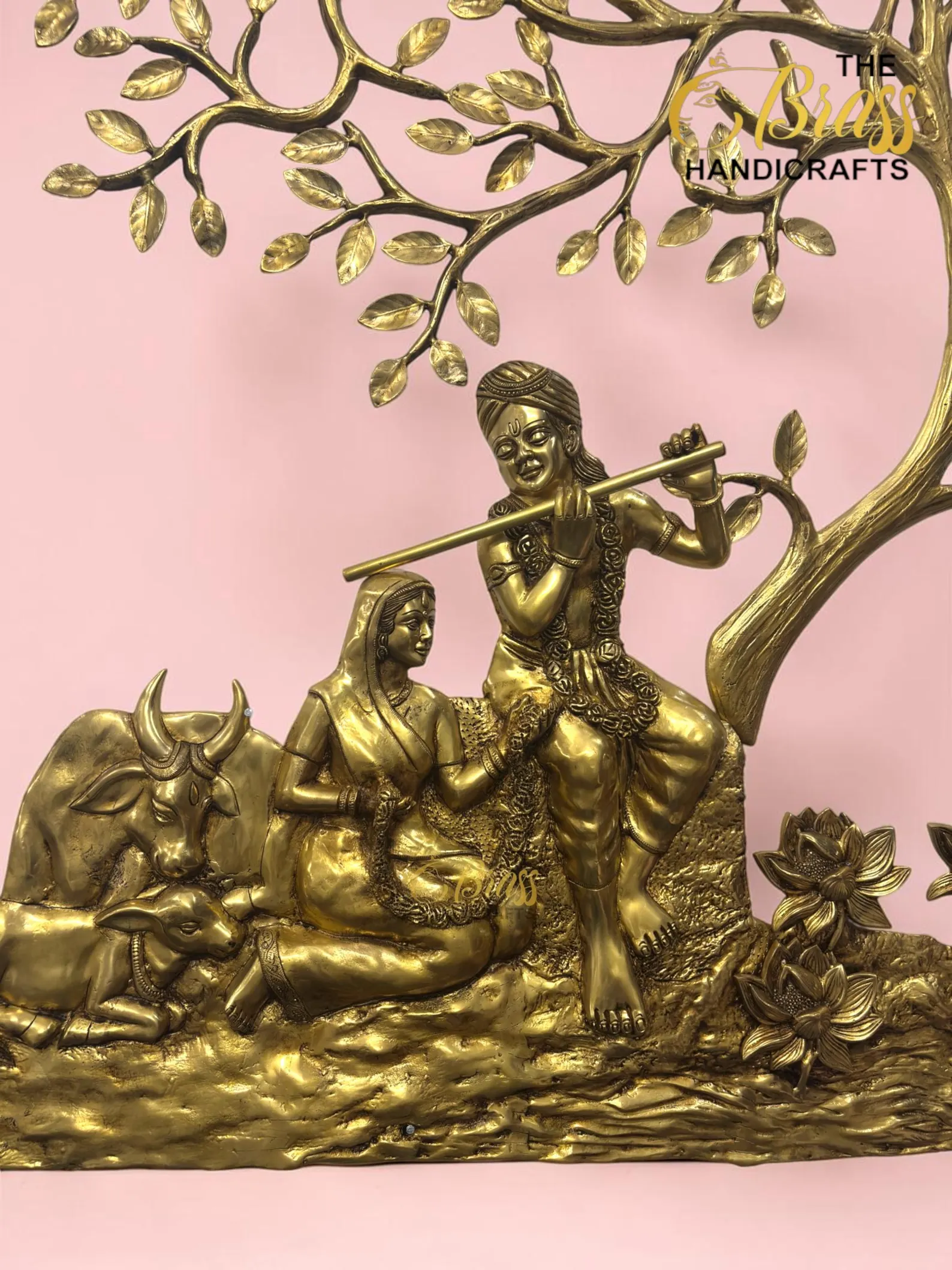 il_1588xN8446713265_ls8l - thebrasshandicrafts.com Gold-toned brass sculpture of a man playing a flute while seated on a cow under a tree against a pink background (decorative handicraft). thebrasshandicrafts.com